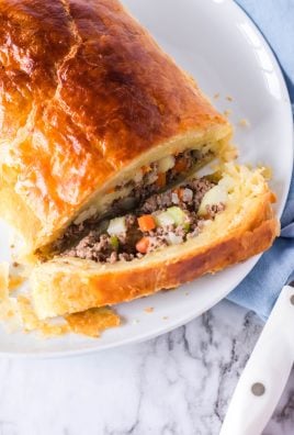 sliced open golden brown ground beef filled wellington on a white platter