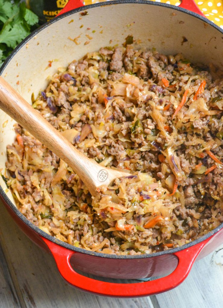 a spoon scooping egg roll in a bowl from the red pot