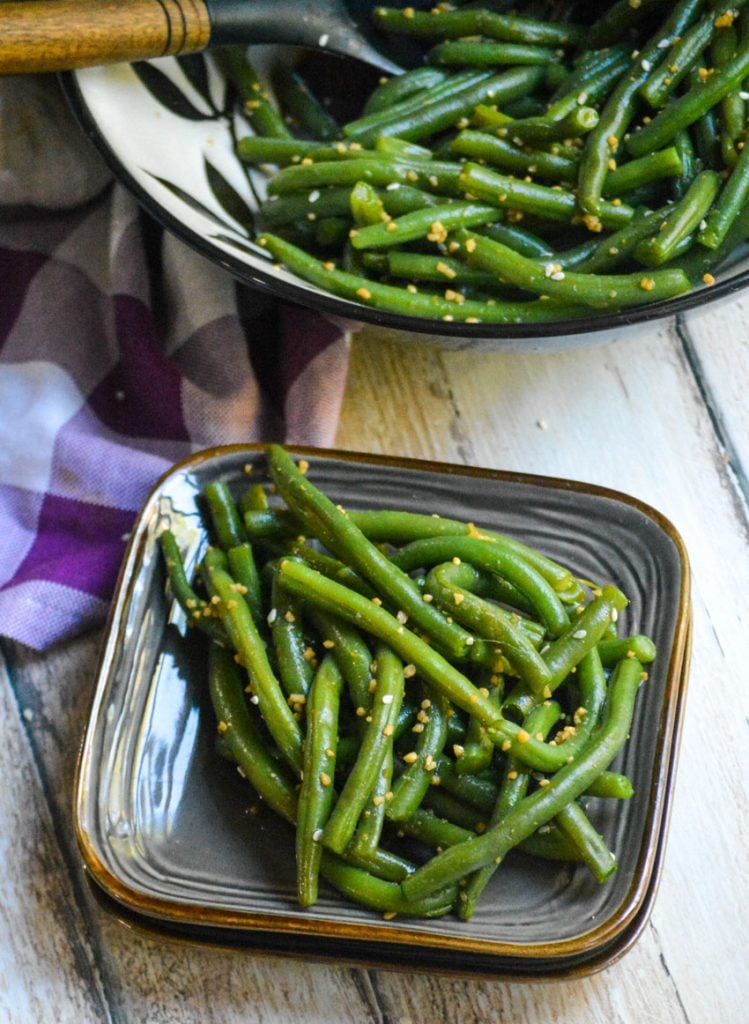 a ceramic bowl is shown filled with garlic ginger green beans