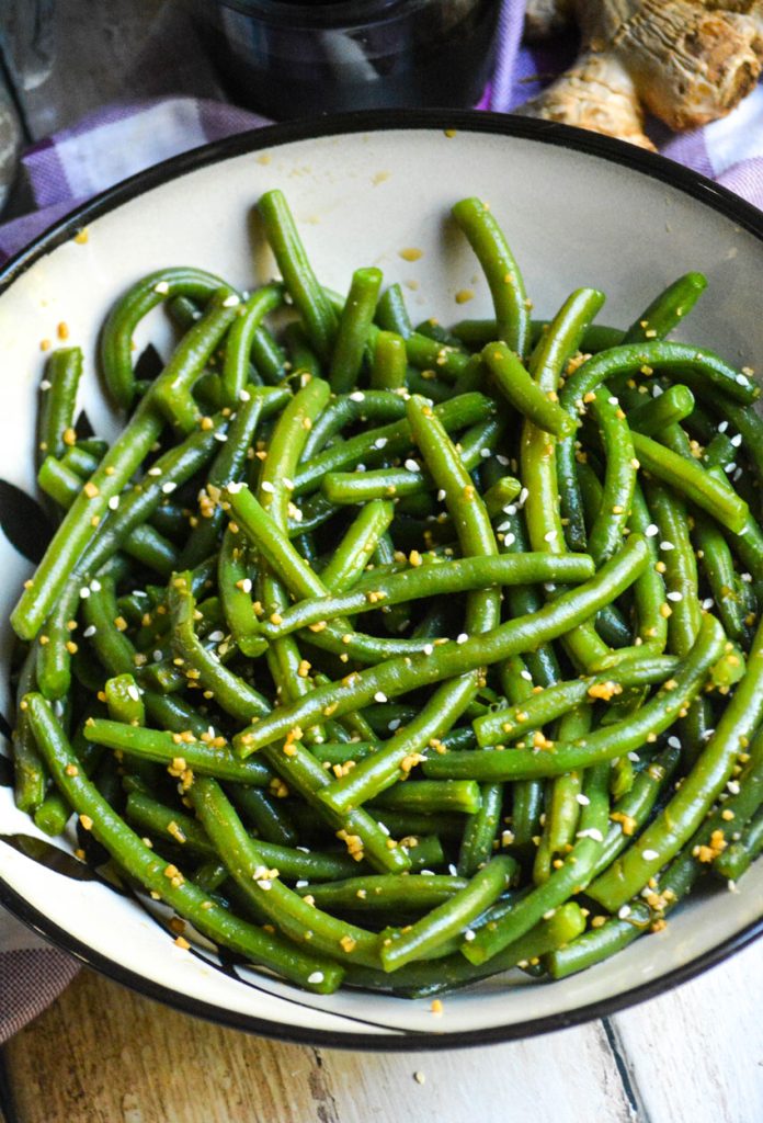 a ceramic bowl is shown filled with garlic ginger green beans