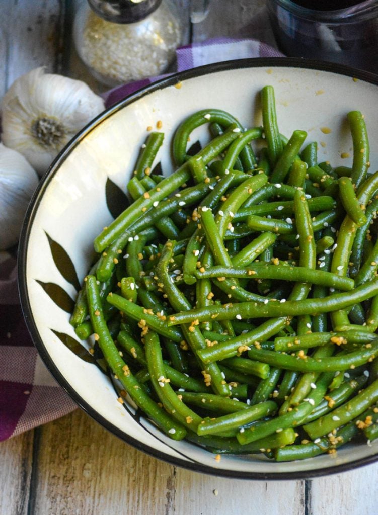 a ceramic bowl is shown filled with garlic ginger green beans