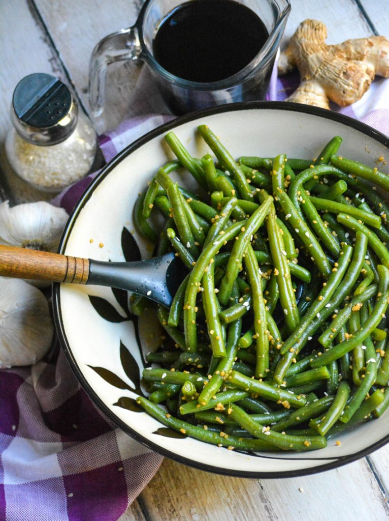 a ceramic bowl is shown filled with garlic ginger green beans