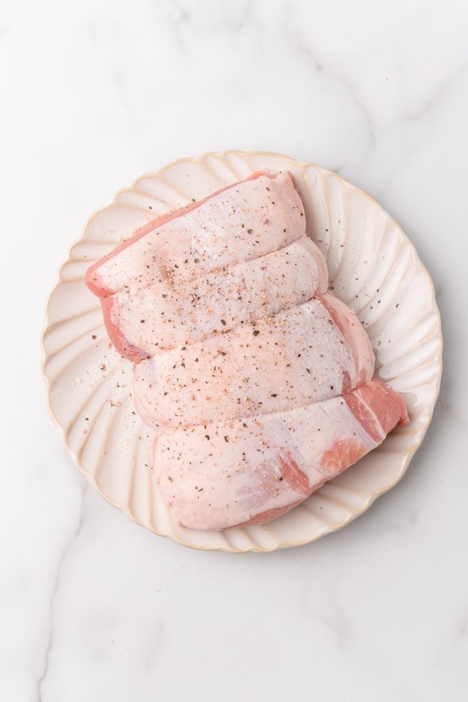 salted and peppered pork loin on a white plate