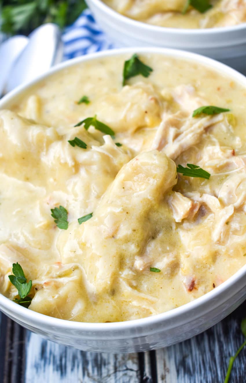 crockpot chicken and dumplings topped with fresh parsley leaves in a white bowl