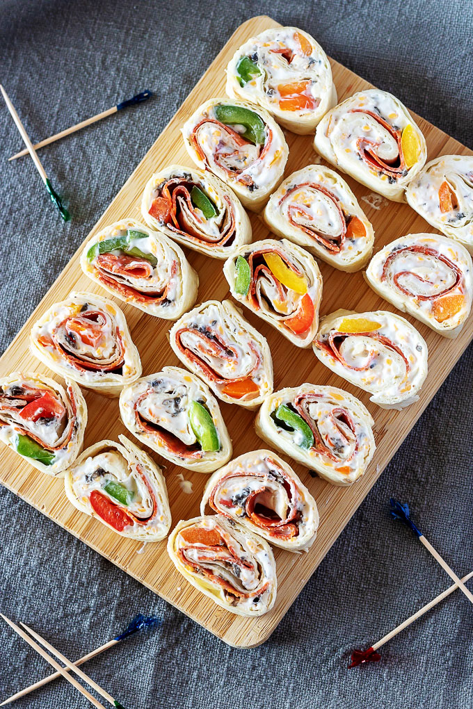 pizza pinwheels shown in even rows on a wooden cutting board