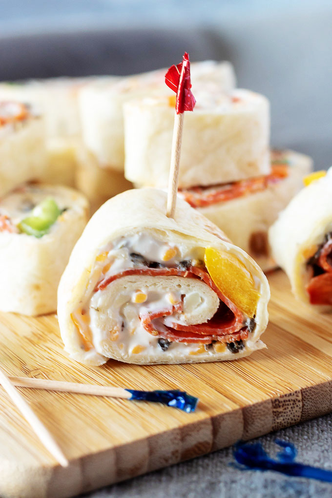 pizza pinwheels shown on a wooden cutting board with toothpicks