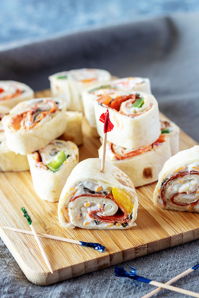 pizza pinwheels served on a wooden cutting board with tooth picks