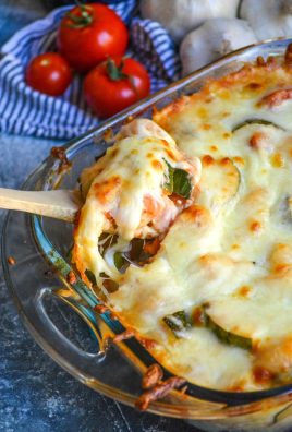 a wooden spoon shown lifting a serving of baked gnocchi with zucchini & tomatoes out of a glass baking dish