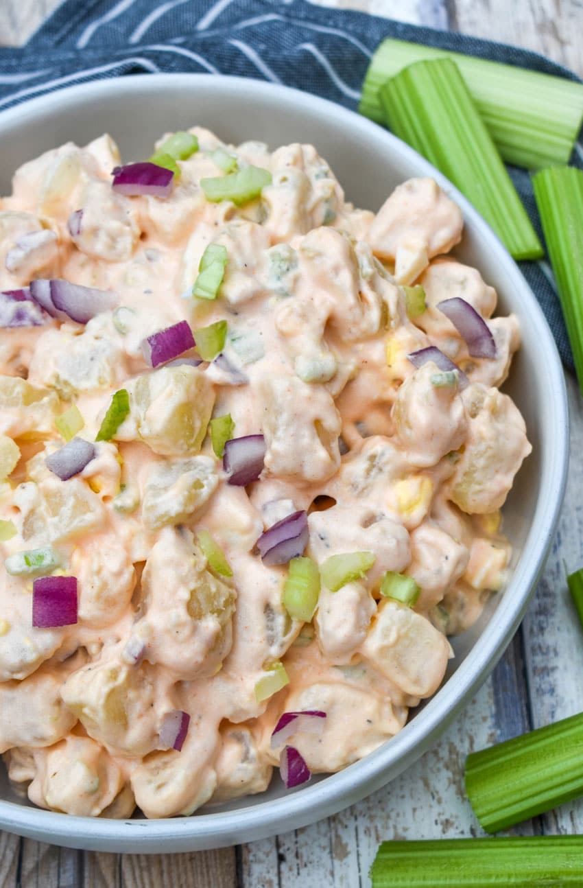 buffalo potato salad in a shallow serving bowl with celery sticks on the side