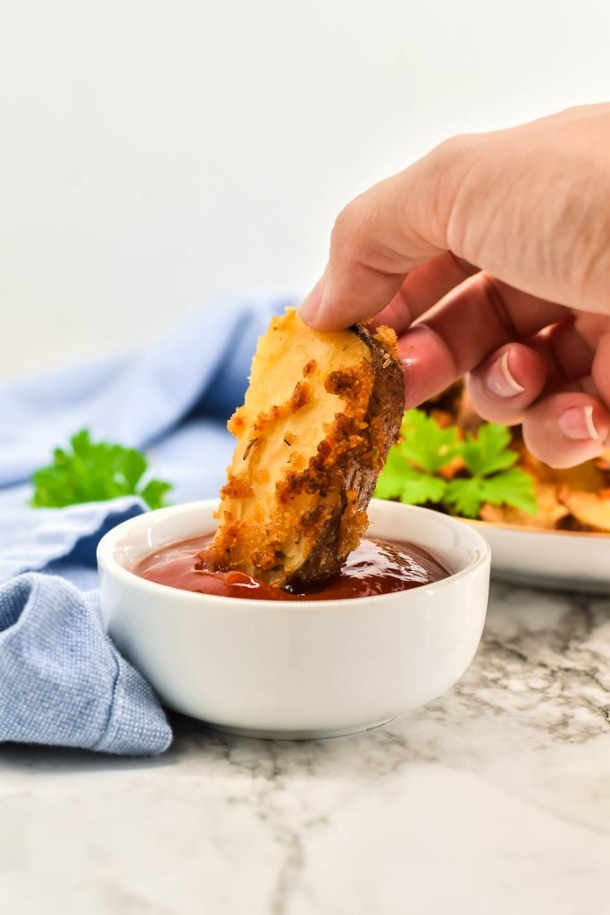 a crispy cheese fry shown being dunked into a white bowl filled with ketchup