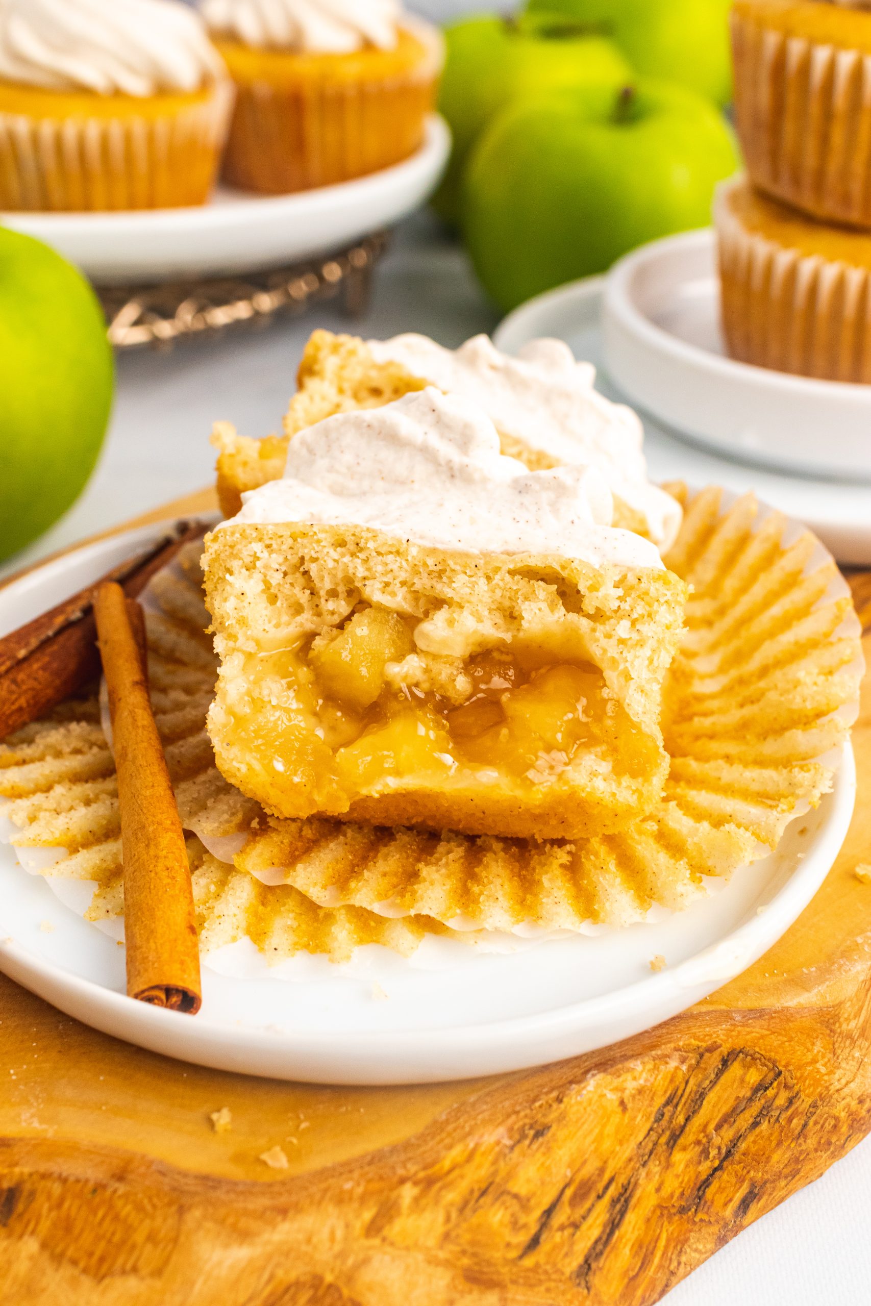 a frosted apple pie cupcake unwrapped and cut in half to reveal the pie filling hidden in the center