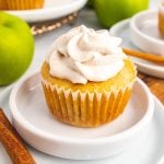 filled apple pie cupcake topped with cinnamon whipped cream & sitting on a small white plate