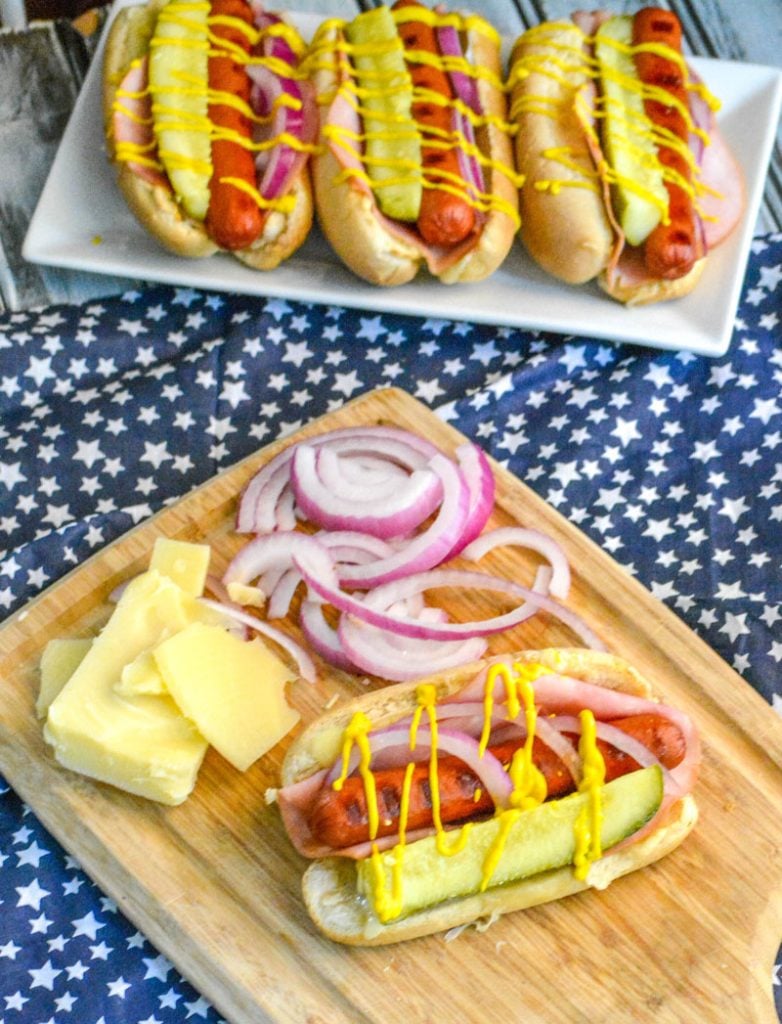 Hot Dogs with swiss cheese, dill pickle, red onion, and yellow mustard