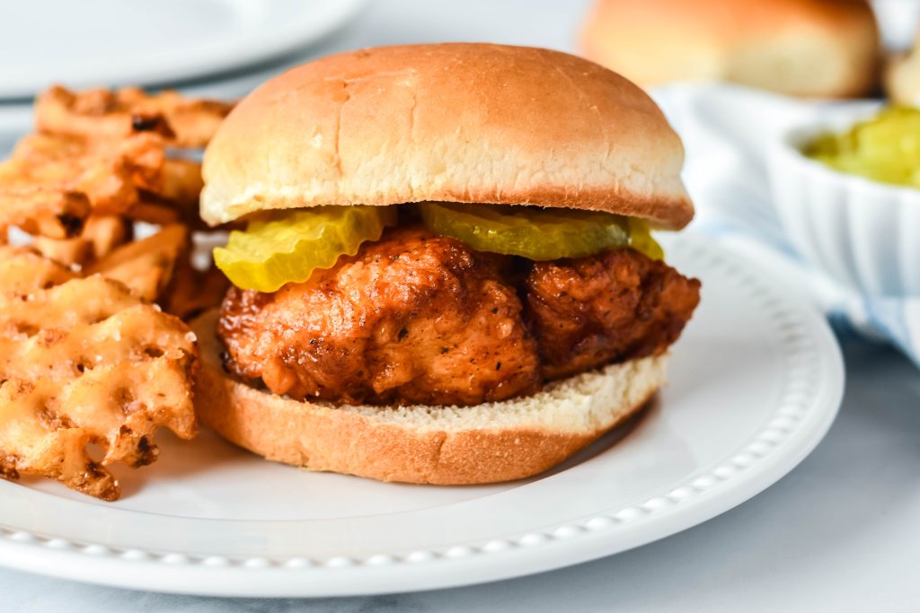 a copycat chick fil sandwich on a white dinner plate with a side of waffles fries