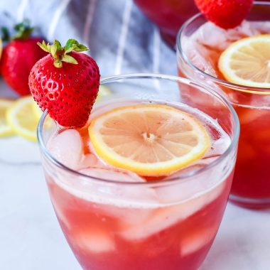 sweet strawberry iced tea served with sliced lemon and fresh strawberry for garnish