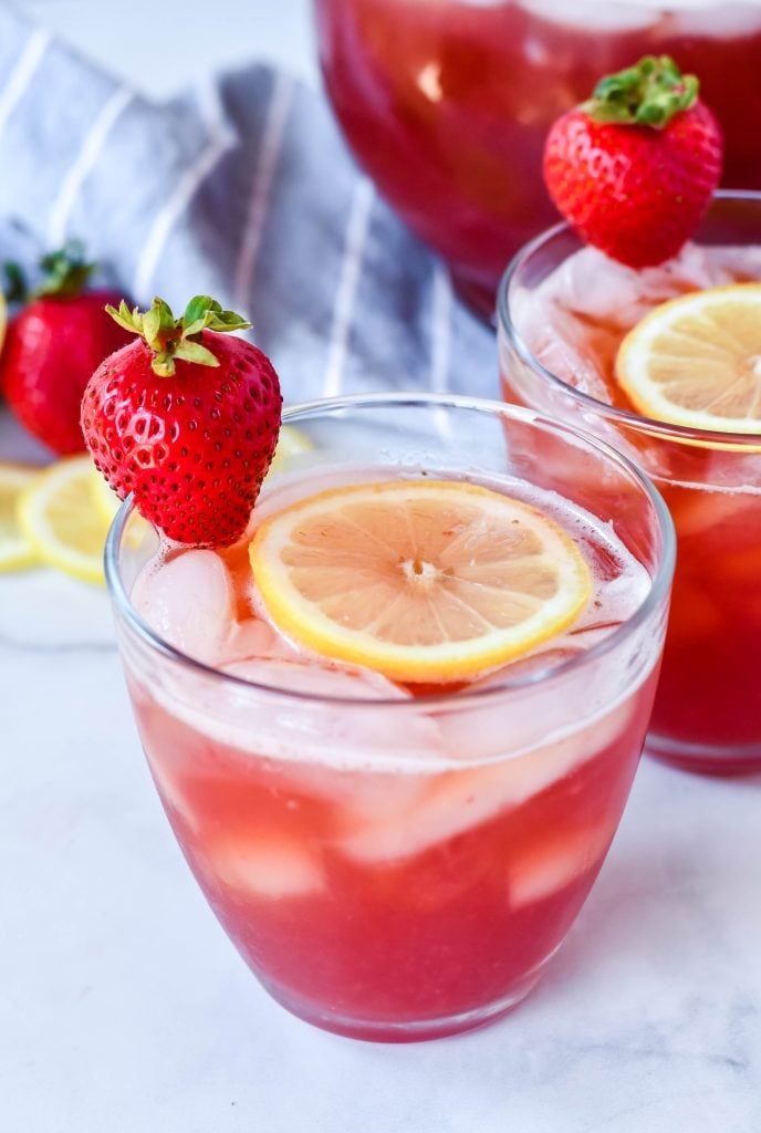 sweet strawberry iced tea served with sliced lemon and fresh strawberry for garnish