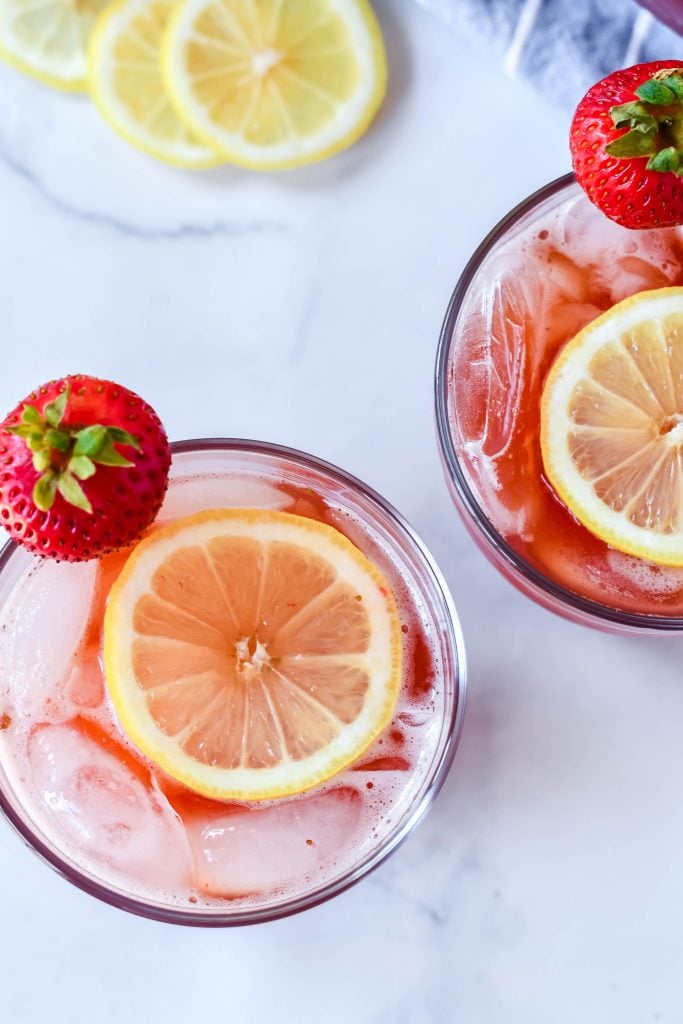 sweet strawberry iced tea served with sliced lemon and fresh strawberry for garnish