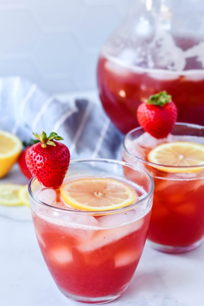 sweet strawberry iced tea served with sliced lemon and fresh strawberry for garnish