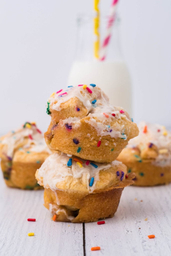 two cake batter monkey muffins stacked on top of each other in front of a glass of milk