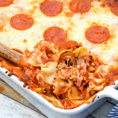 a wooden spoon digging into a meat lovers pizza casserole in a white dish