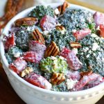 creamy strawberry broccoli salad studded with pecans and served in a white bowl