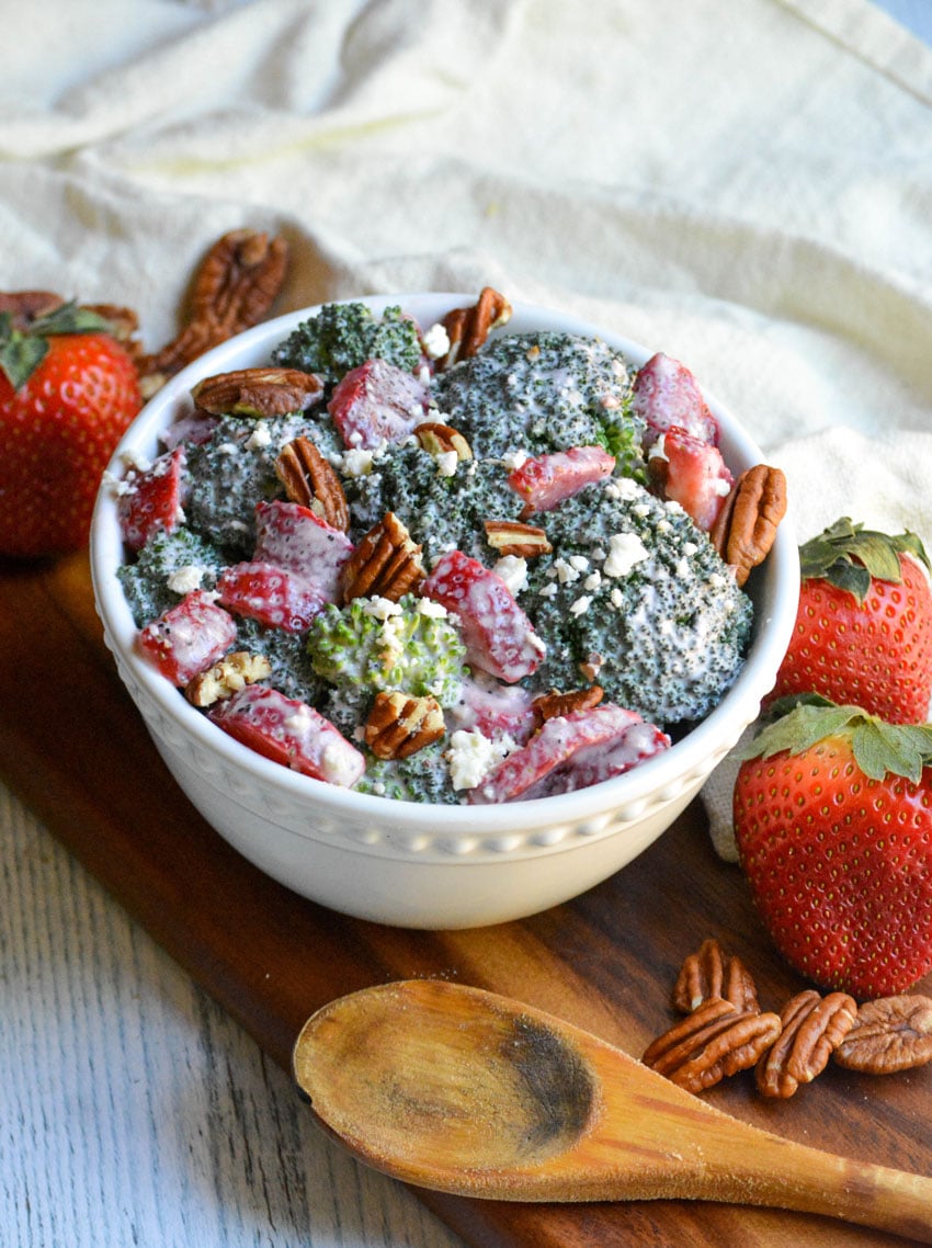 sweet strawberry broccoli salad in a white bowl on a wooden cutting board