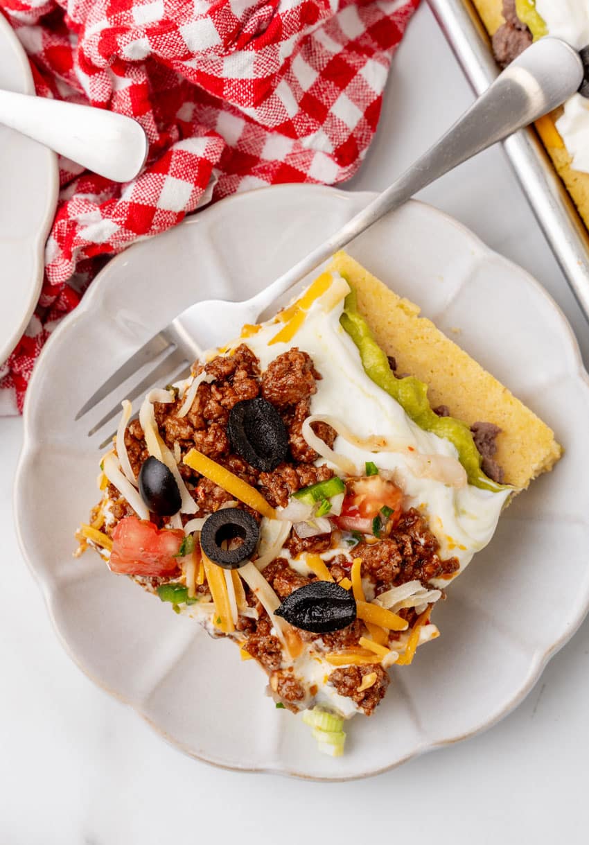 a slice of 7 later sheet pan cornbread casserole on a white plate