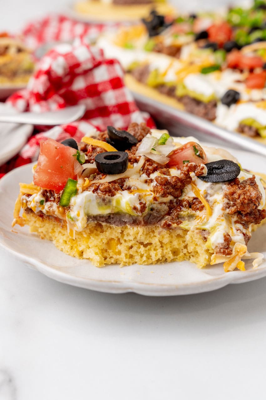 a slice of 7 later sheet pan cornbread casserole on a white plate