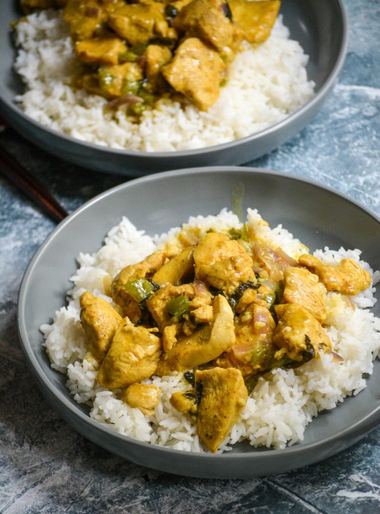 two helpings of Basil Chicken in Coconut Curry Sauce spread over a bed of steamed white rice in a gray bowl