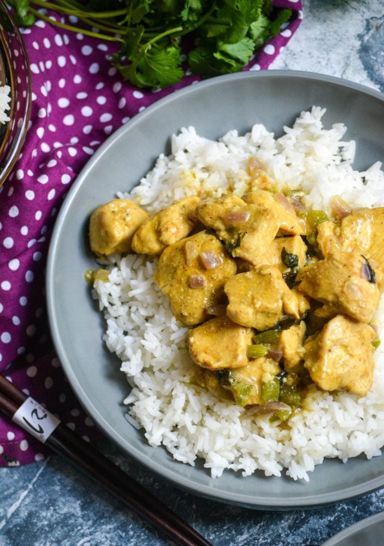 BASIL CHICKEN WITH COCONUT CURRY SAUCE OVER A BED OF STEAMED WHITE RICE IN A SHALLOW GRAY BOWL