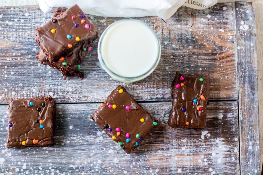 cosmic brownies on a weathered wooden back drop shown with a full glass of milk