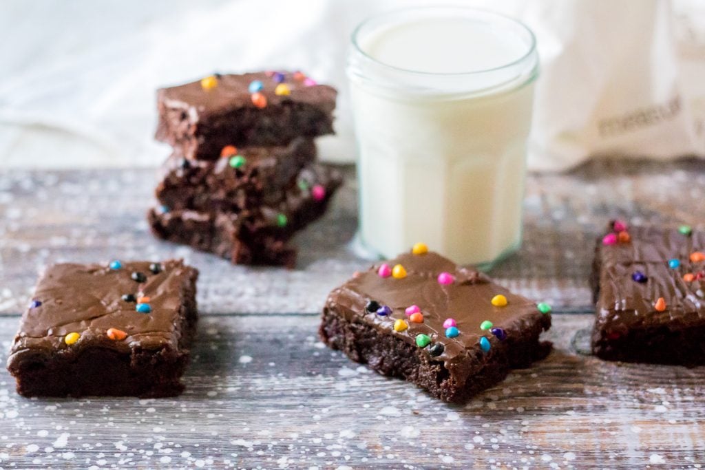 cosmic brownies on a weathered wooden back drop shown with a full glass of milk