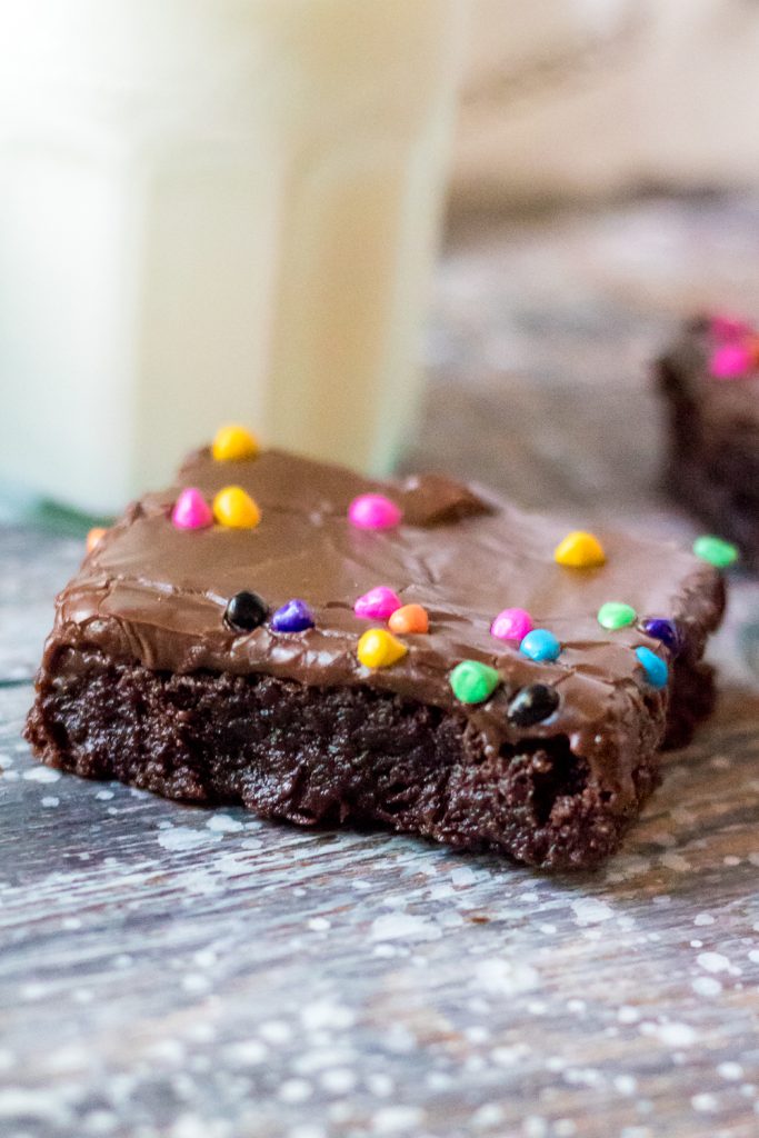 Cosmic brownie on a weathered wooden back drop with a glass of cold milk