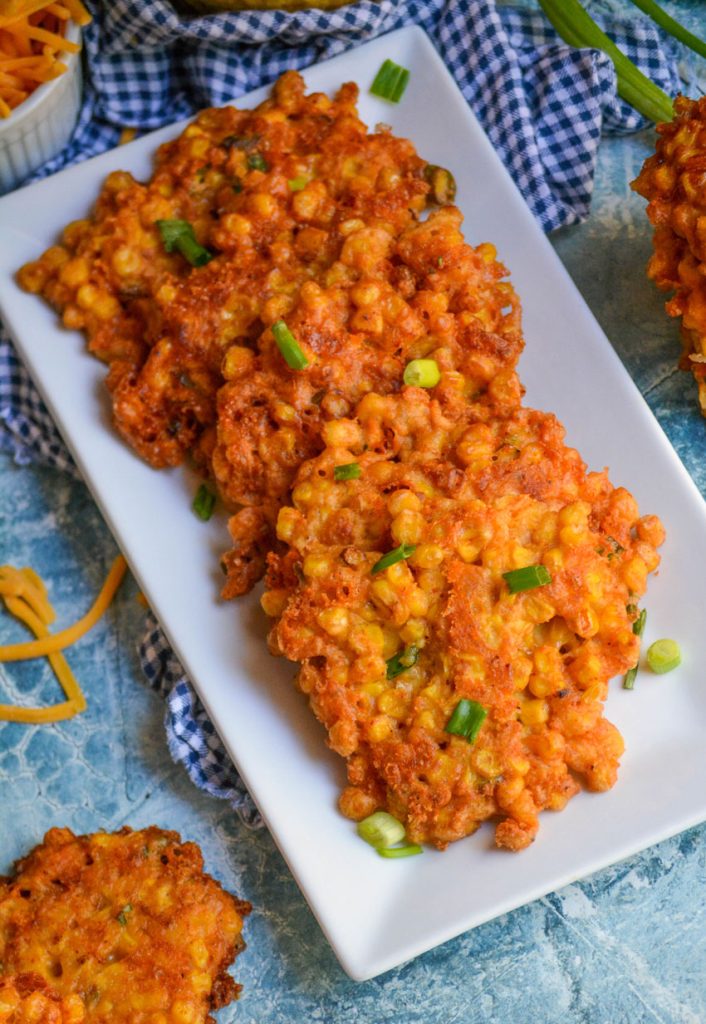 sweet corn cheddar cheese fritters served stacked on an white appetizer tray