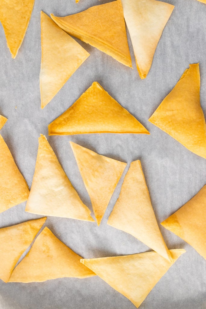 golden brown crispy baked wonton chips on a piece of parchment paper