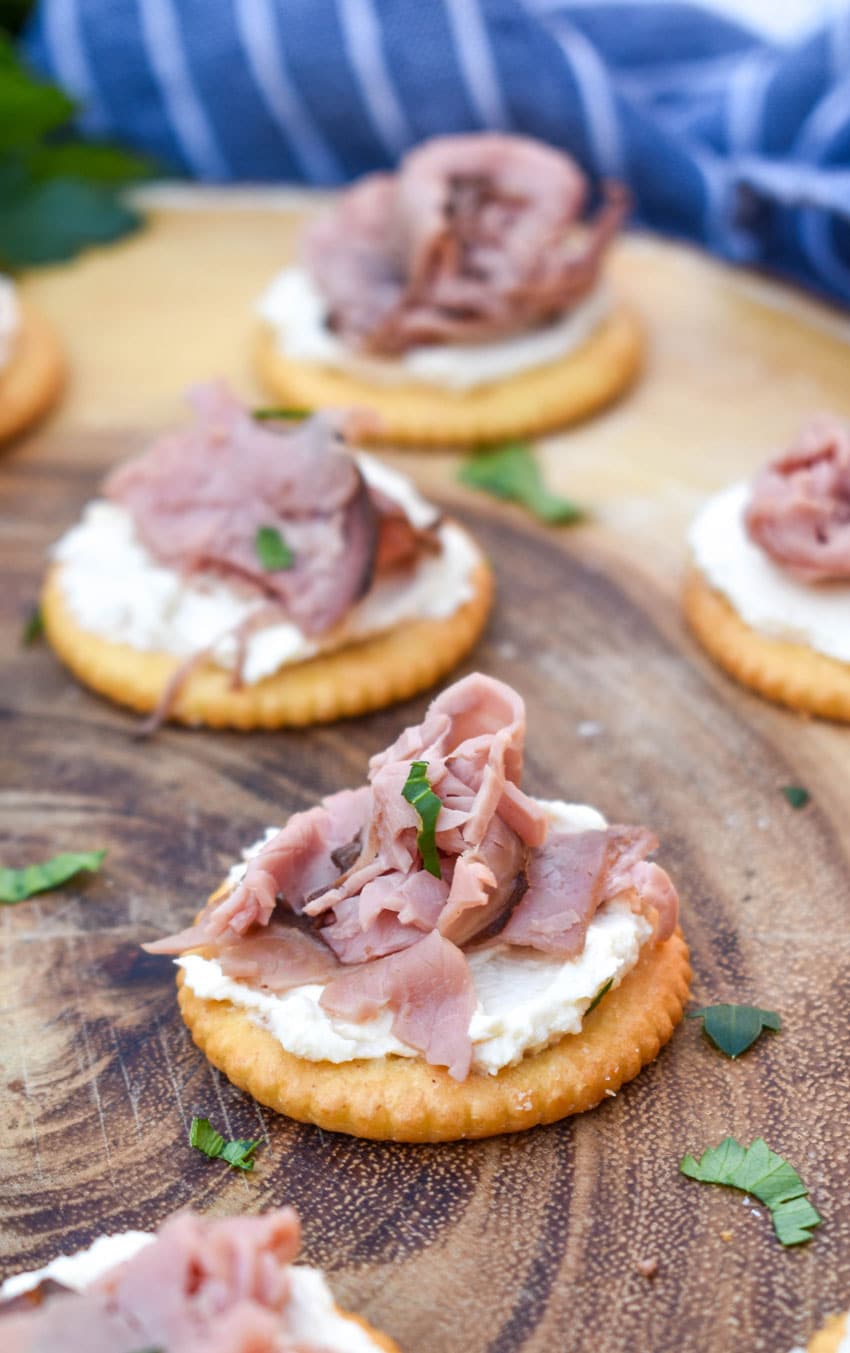 roast beef and horseradish cream cheese crackers on a wooden cutting board