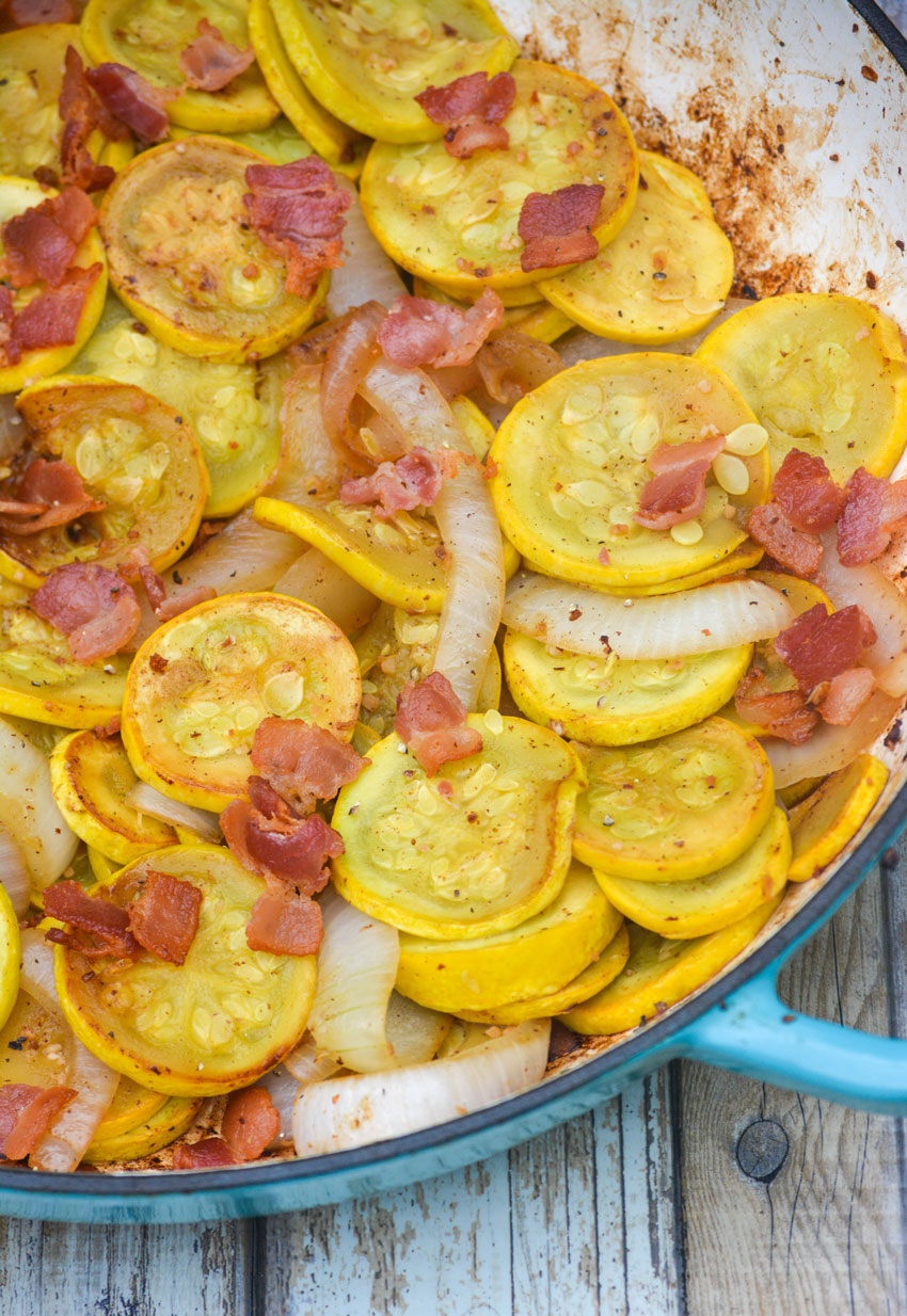 sauteed summer squash with onions & bacon in a blue cast iron enameled skillet