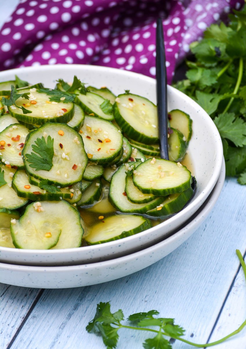 a black spoon in a bowl of Asian cucumber salad