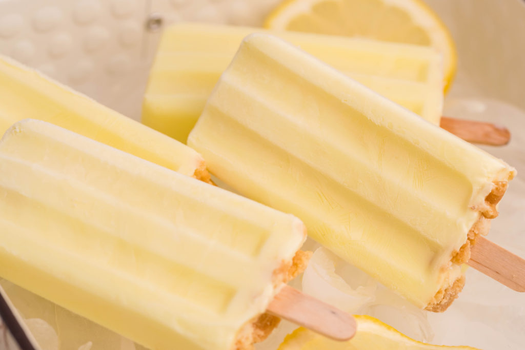 lemon pie pops shown over a bed of ice cubes and lemon slices