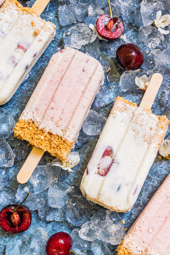 cherry cheesecake popsicles laid out over ice cubes