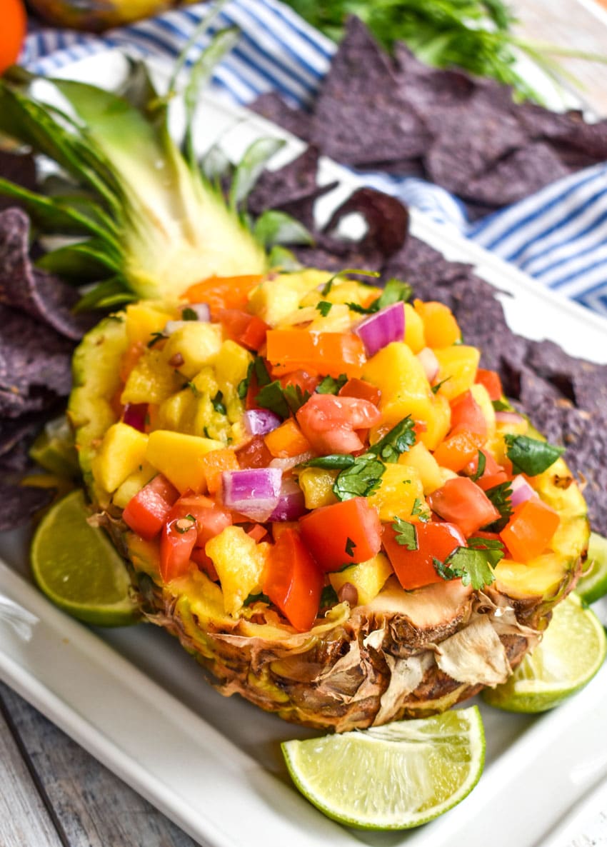 pineapple mango salsa in a hollowed out fresh pineapple on a white serving platter