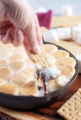 a hand holding a graham cracker dipped in easy skillet s'mores dip