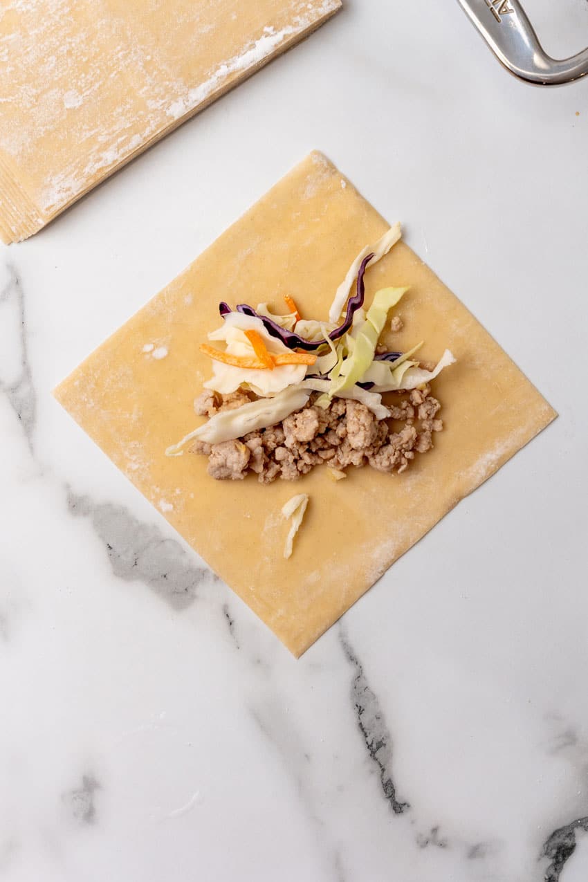 ground pork and shredded cabbage in the middle of an egg roll wrapper