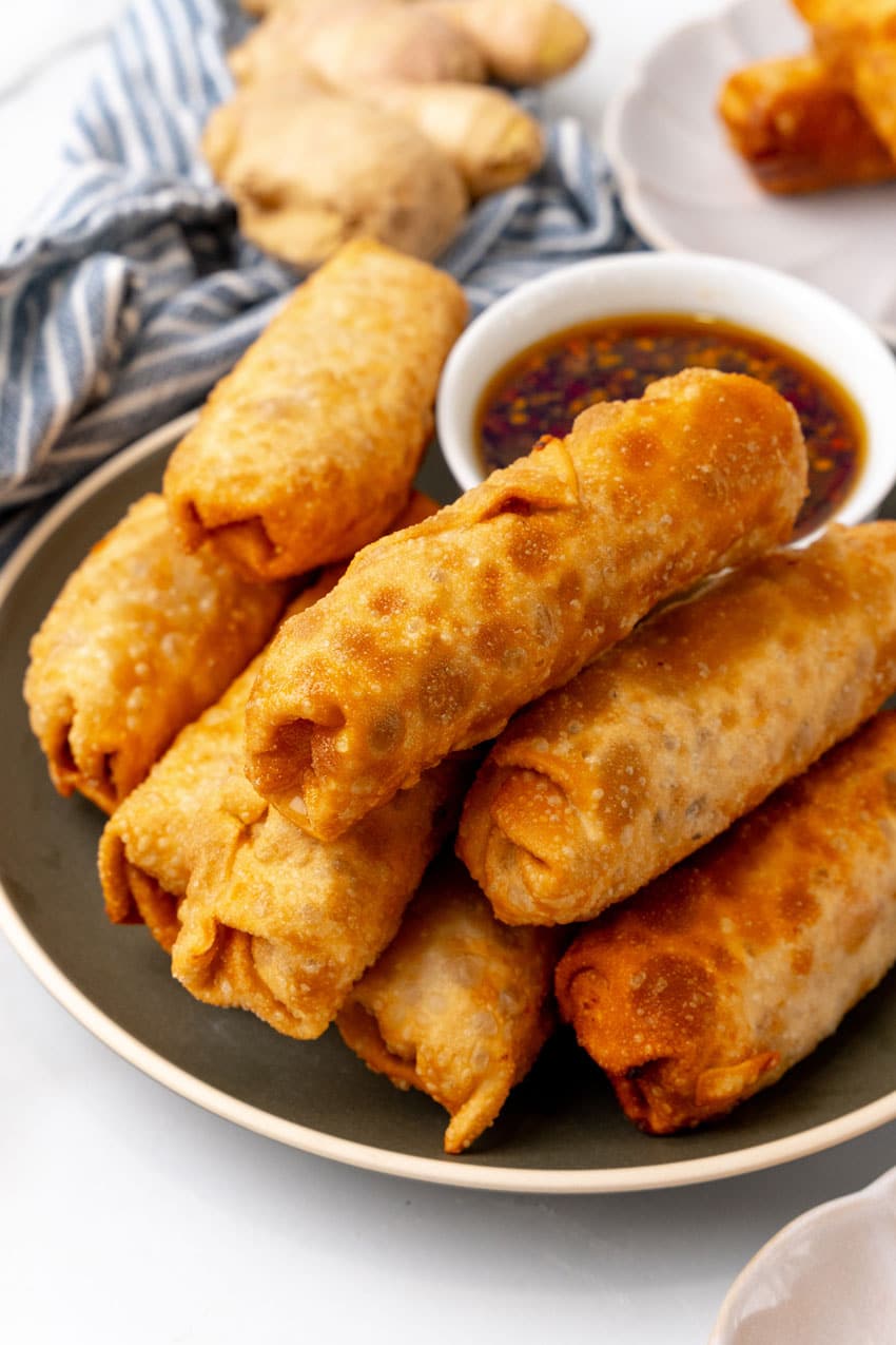 a pile of crispy fried homemade egg rolls resting on a green plate