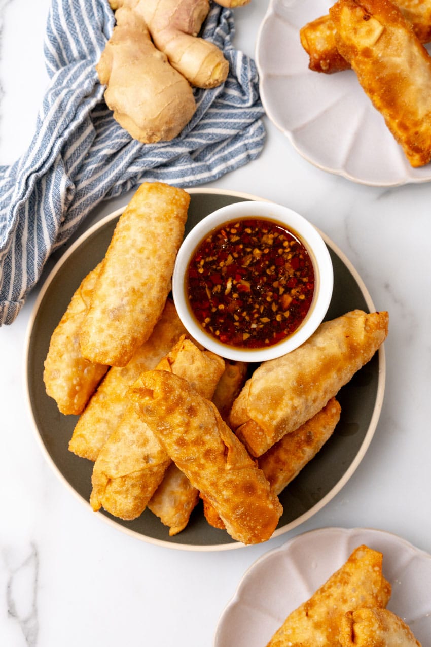 a pile of crispy fried homemade egg rolls resting on a green plate