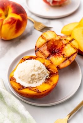 a grilled peach topped with vanilla ice cream on a white dessert plate