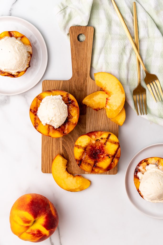 grilled peach halves on a wooden cutting board