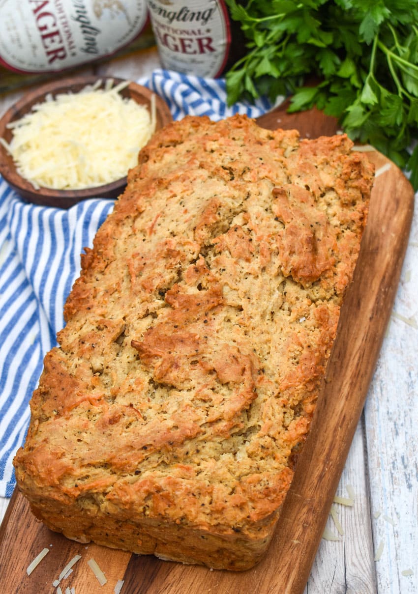 a loaf of black pepper parmesan beer bread on a wooden cutting board