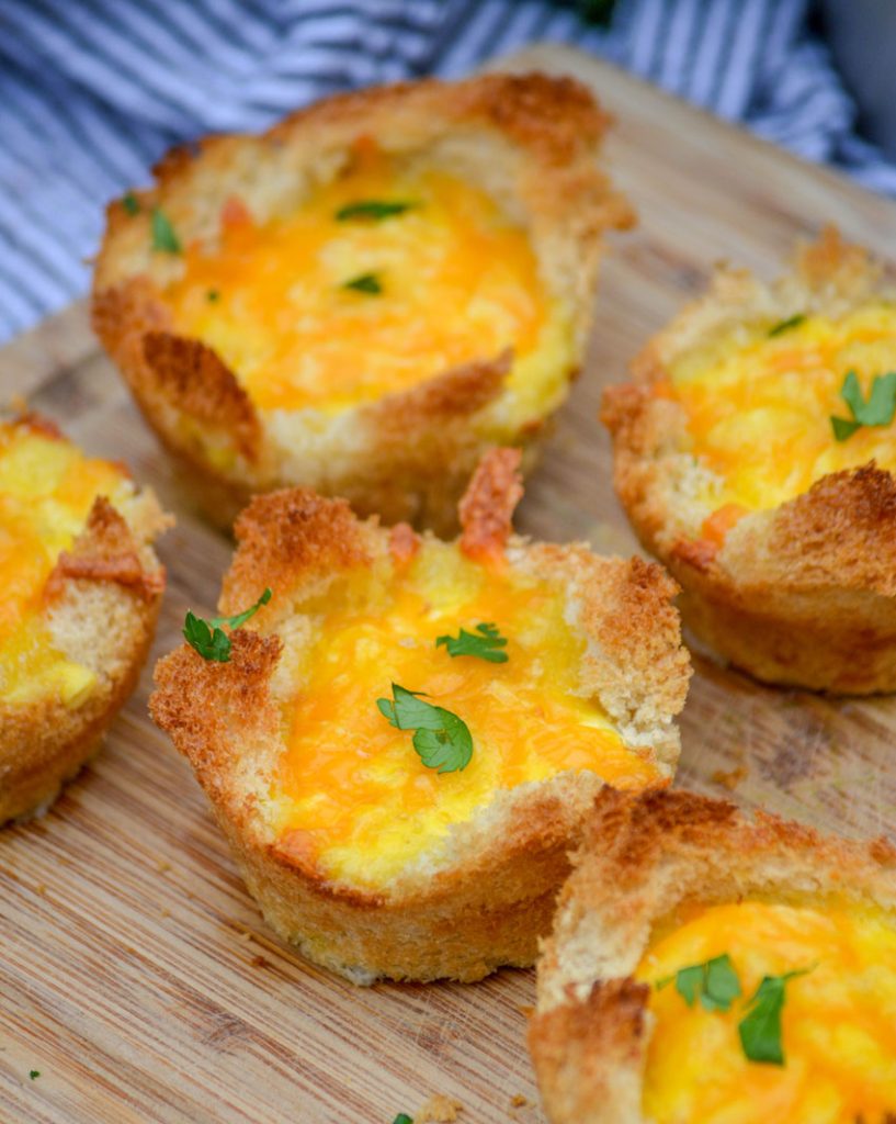 Ham, Egg, & Cheese Toast Cups on a brown cutting board with a striped cloth napkin in the background