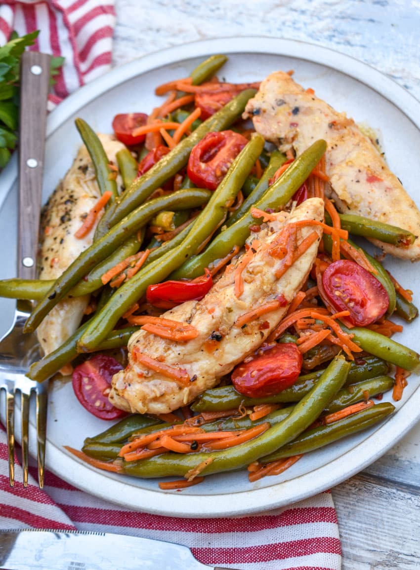 one pot balsamic chicken and veggies on a white plate with a fork resting on the side